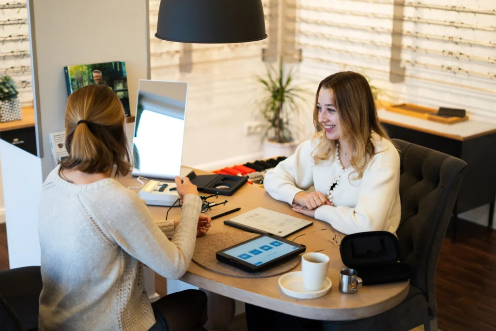 Mitarbeiterin von Fehntjer Optik berät Kundin persönlich bei der Auswahl einer Brille in entspannter Atmosphäre im Geschäft